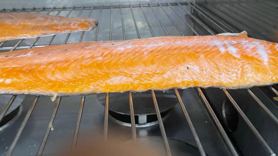 Two salmon filets being smoked on a metal grid