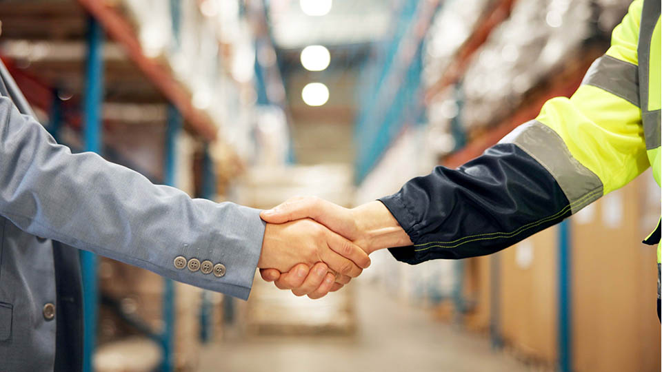 Closeup, distributor or supplier shaking hands in aisle for shipping