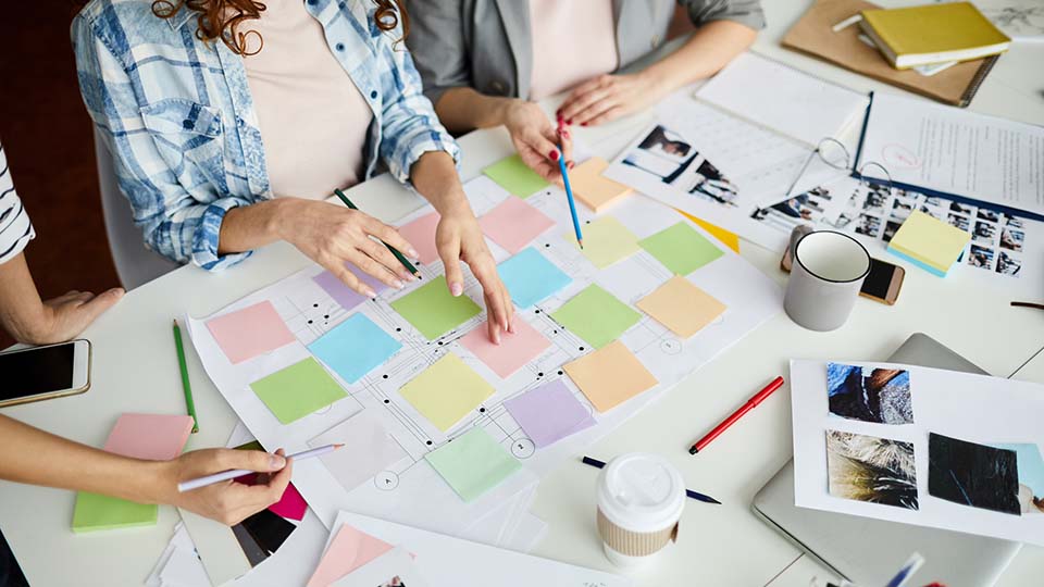 High angle closeup of contemporary business team planning project placing colorful stickers on roadmap