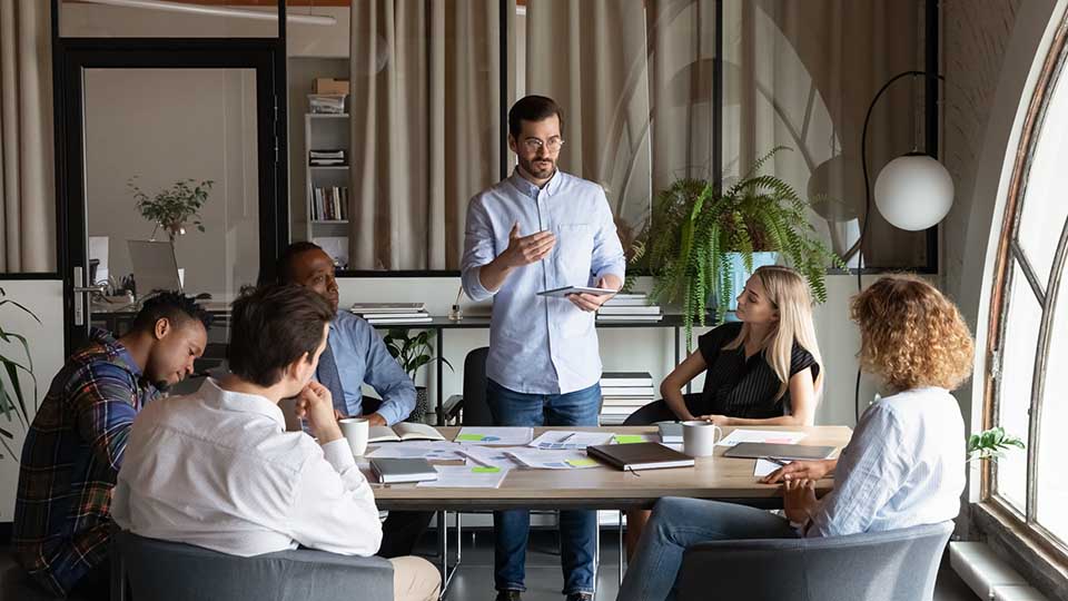 Confident business team leader speaking to employees at corporate meeting
