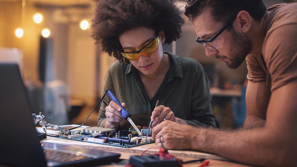 Woman Soldering a circuit board in her office