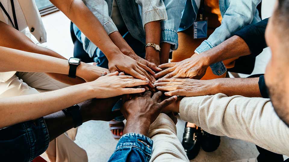 Diverse group of hands joined together, representing teamwork and unity