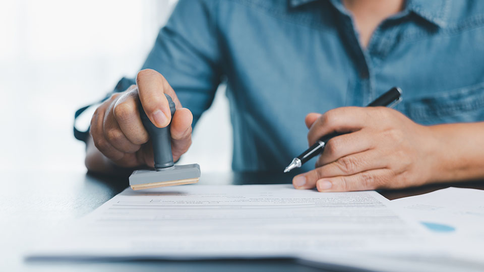 Businessman hands stamp approve on financial business approval document paper