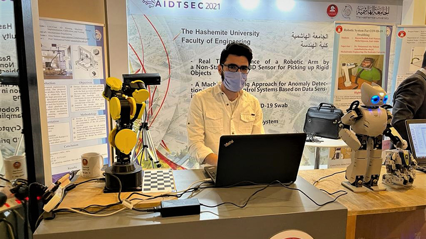 Researcher at the Hashemite University Faculty of Engineering working on a laptop with robots on the table