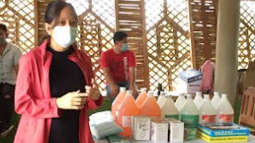 Pia Zamora, with a mask on, standing next to a table full of medical equipment, giving explanations