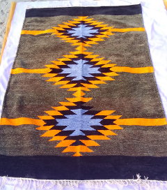 A Shataranji carpet with geometrical designs brightly colored against a purple background