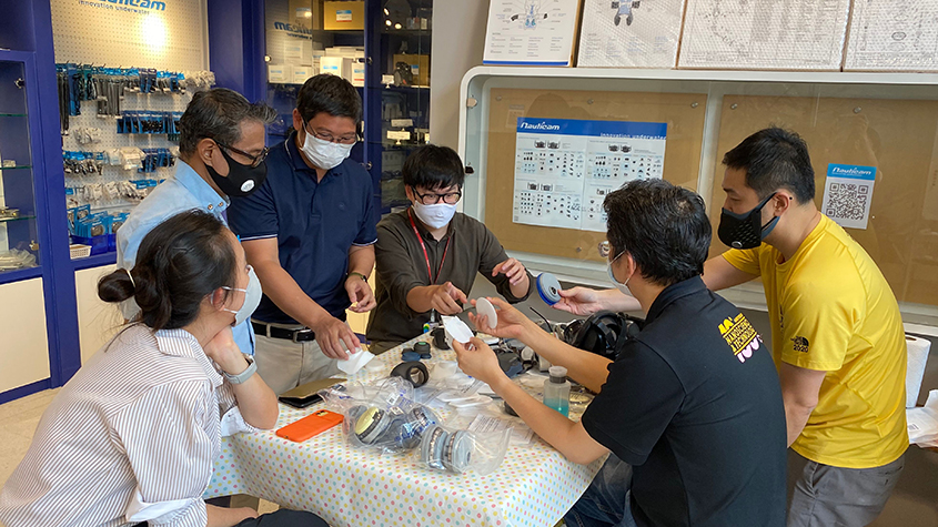 CUre Enterprise’s team of researchers around a table discussing the CUre Air Sure Mask prototype