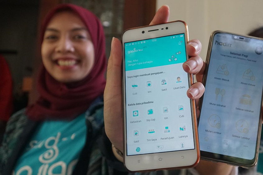 Afia Fitriati, co-owner of Fast8, holding a smart phone featuring the Gadjian app with many icons