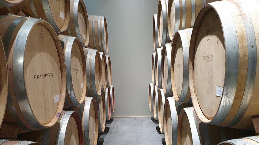 A row of large stacked wooden GranMonde wine barrels