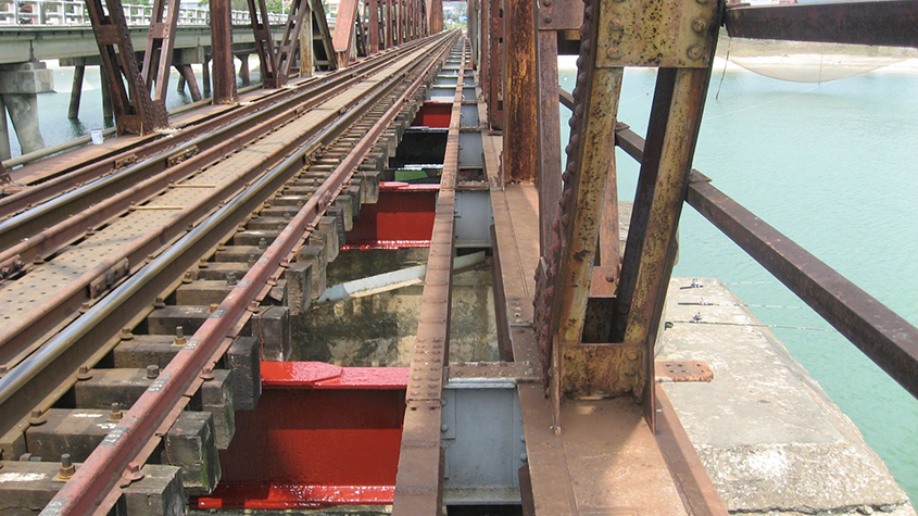 The Nam o Bridge in Da Nang with train tracks and fresh red painted beams in the low structure