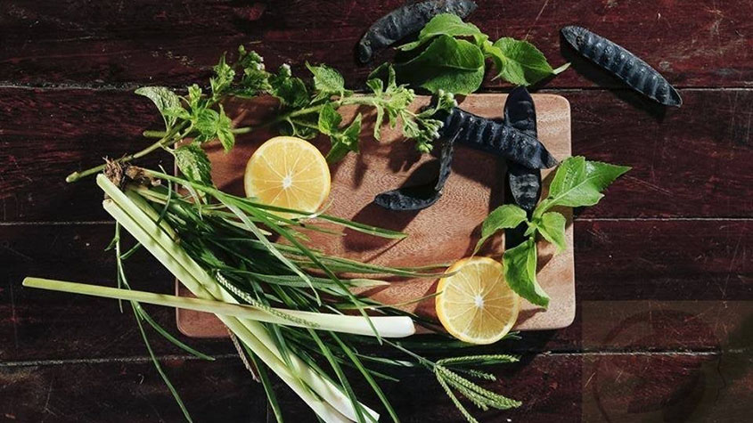 Two lemon halves and several herbs used by Sao Thai Duong Company on a chopping board