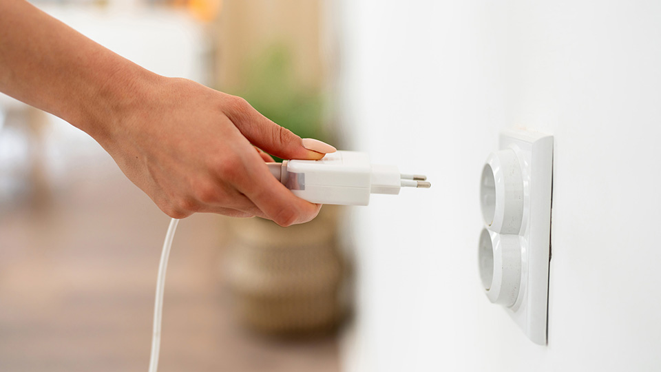 Woman's hand plugging cable in an electrical socket