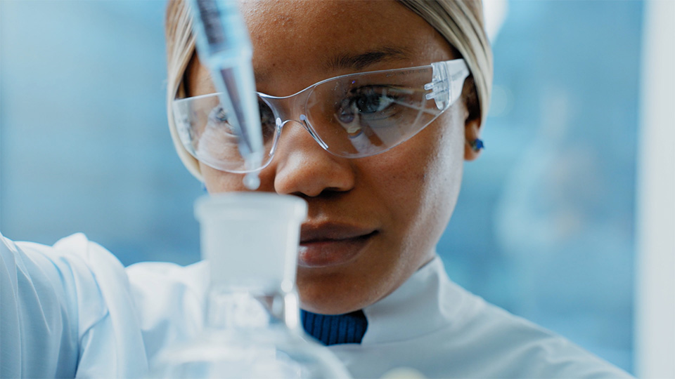 Scientist putting liquid in a bottle with a dropper