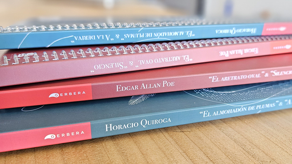 Se ven cuatro libros en primer plano. En los lomos se ven los títulos de obras literarias, a saber, <i>El almohadón de plumas</i> y <i>A la deriva</i>, de Horacio Quiroga, y <i>El aretrato oval</i> y <i>Silencio</i>, de Edgar Allan Poe. Los libros incluyen la marca “Gerbera”. Las cubiertas son de color rojo y azul.