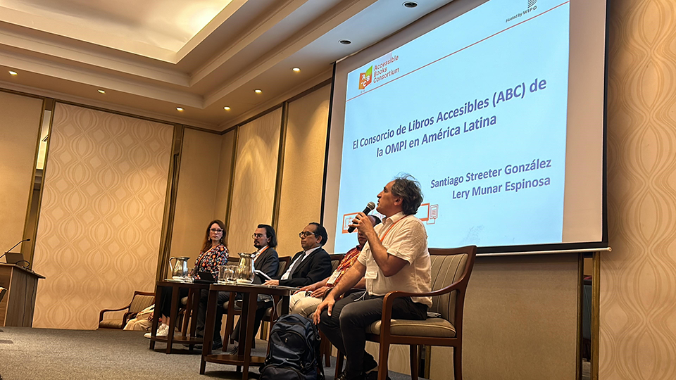 Cuatro panelistas sentados en el escenario de la sala de talleres. Pablo Lecuona, de Tiflonexos, habla por el micrófono.