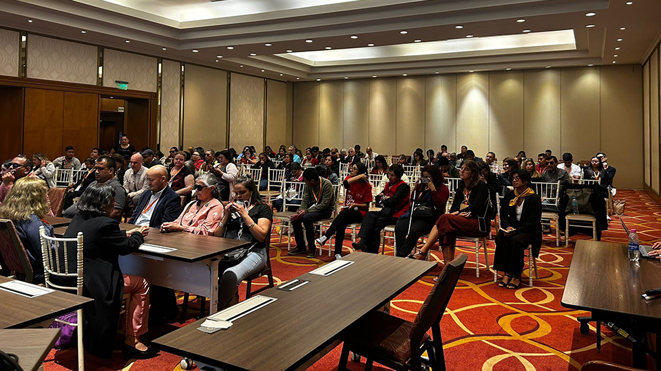 Asistentes al taller organizado por el ABC y la ULAC, sentados en filas de sillas en una gran sala, con grupos focales participando al frente en discusiones de mesa redonda.