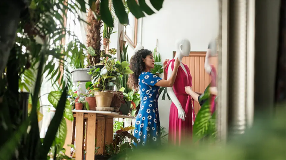 a fashion designer adjusting a dress on a mannequin