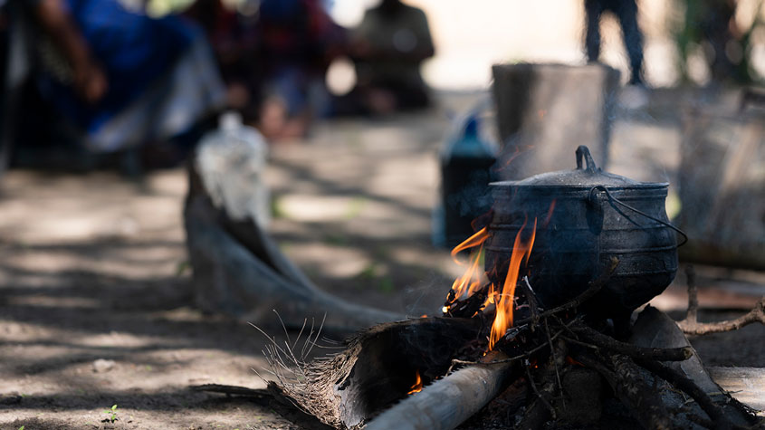 Photo of a fire being used to boil mokola palm leaves with natural dye