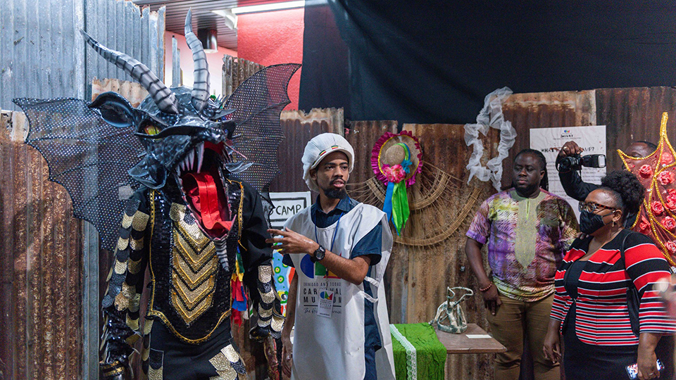 A tour guide at the Trinidad and Tobago Carnival Museum explains a traditional character to visitors at "The Story of Jouvay" exhibition
