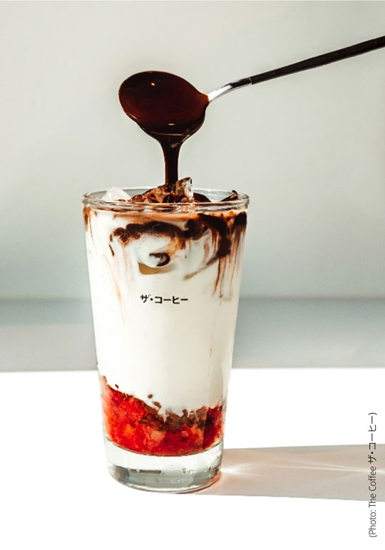Photo shows one of Coffee ザ・コーヒー's signature beverages with fruit cream and coffee being poured n top from a spoon.