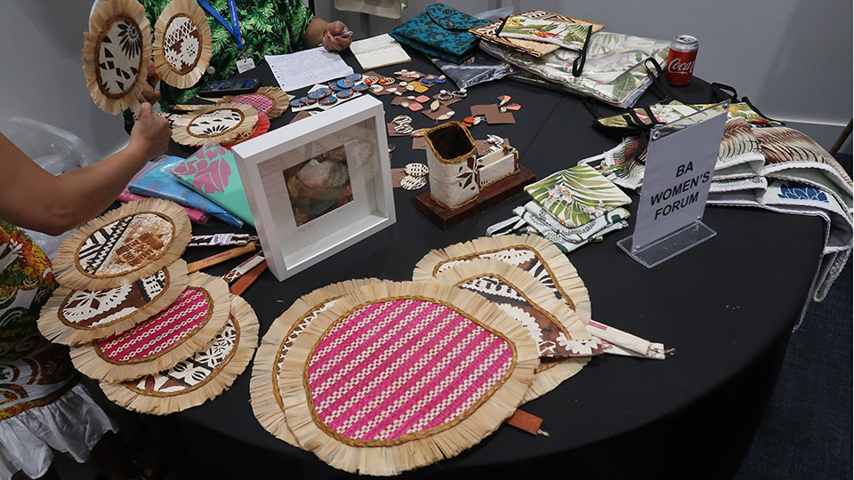 : A table with several handcrafted items, including fans, colorful pouches, and earrings