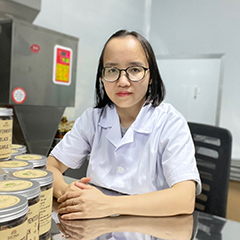 Dr. Nguyen Thi Ngoan is the CEO of Biona, in a white lab coat, sitting at a desk with fermented black garlic boxes