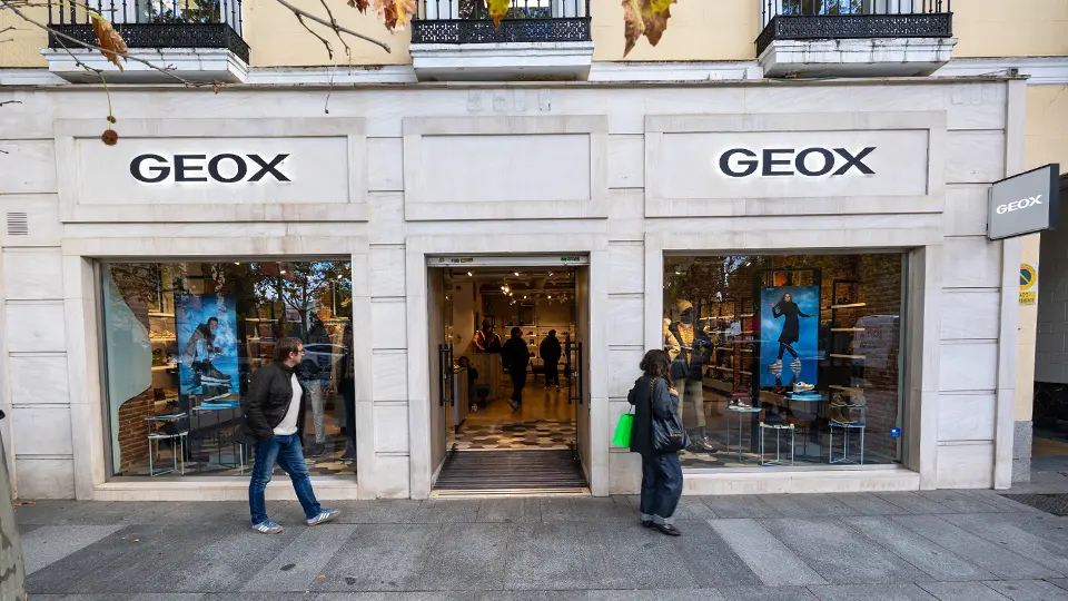 People walking past the geox storefront in the commercial district of madrid, spain