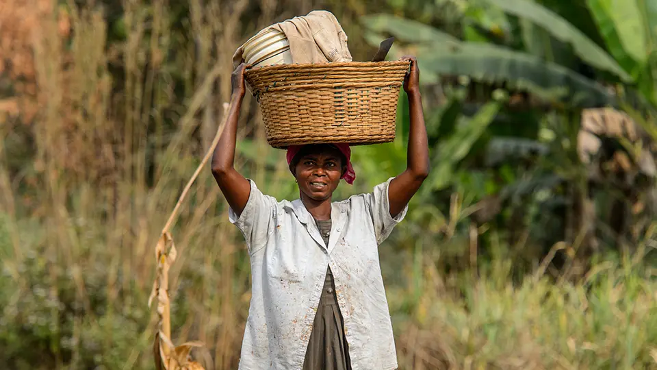 Ghanaian woman carries a basket on her head along the road