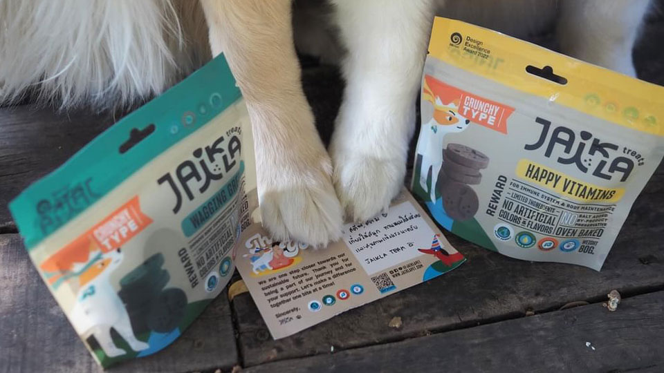 Dog paws resting beside Jaika dog treat packages featuring natural reward snacks and vitamin treats.
