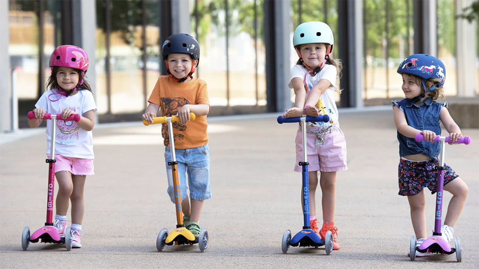 Four children riding a Micro Mobility Scooter