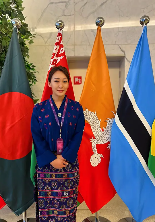 Pema Deki posing in front of flags during an official visit where she was performing