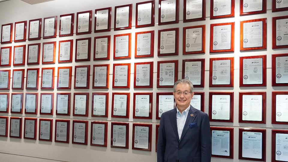 Takashi Eto, director ejecutivo de Topcon, posando delante de los certificados de patente de la empresa