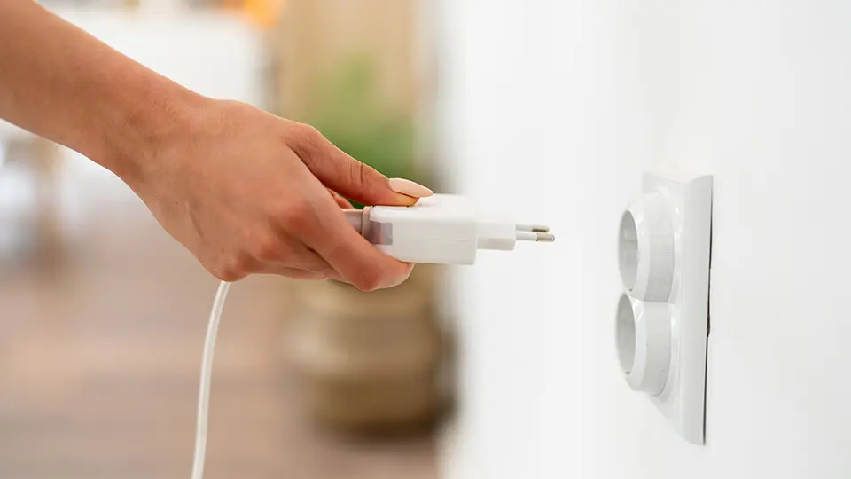 Woman's hand plugging cable in an electrical socket