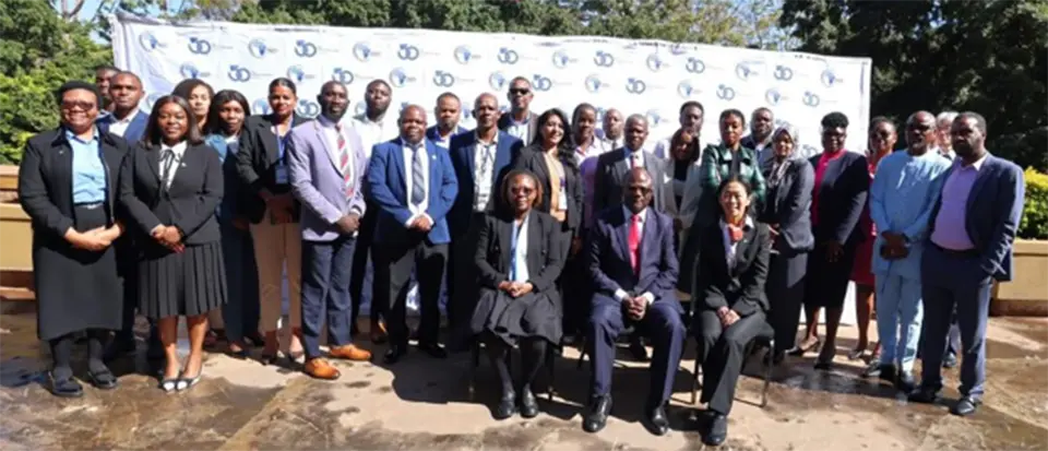 Group photo of professionally dressed delegates at outdoor event with 30th anniversary banner