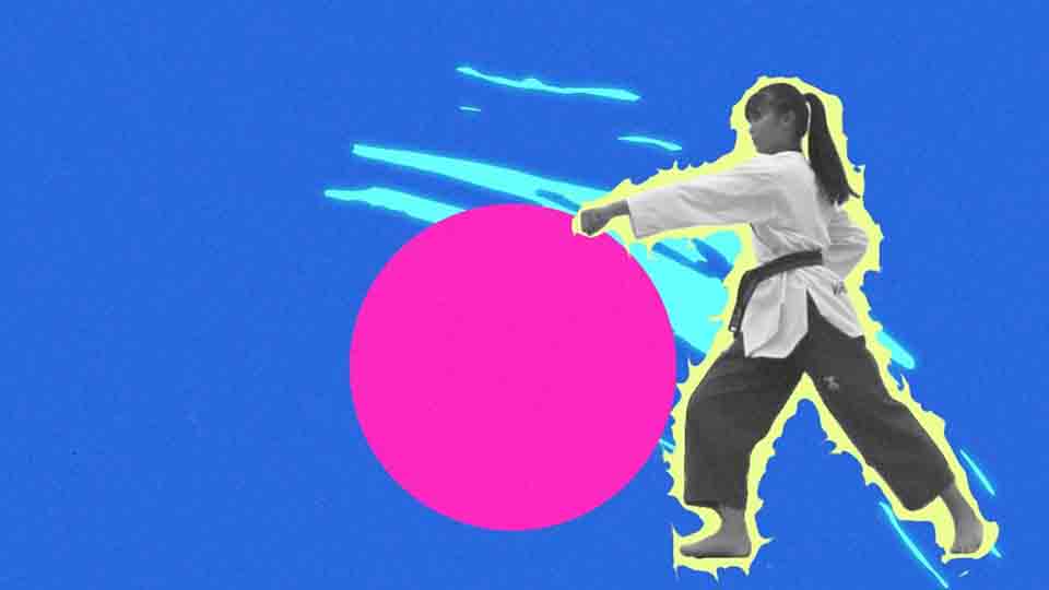 A black-and-white photo of a female martial artist in a white gi and black belt performing a punch stance