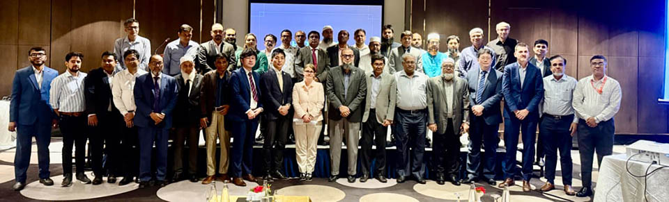 Large group of professionals posing for a formal group photo at a conference or official meeting in a hotel or convention center setting.