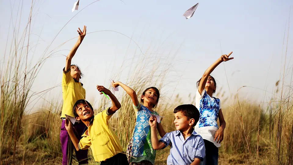Children playing airplane paper outdoor in the nature