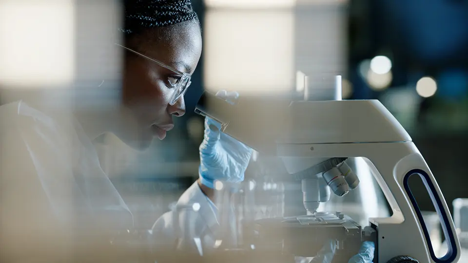 Scientist in a lab looking through a microscope