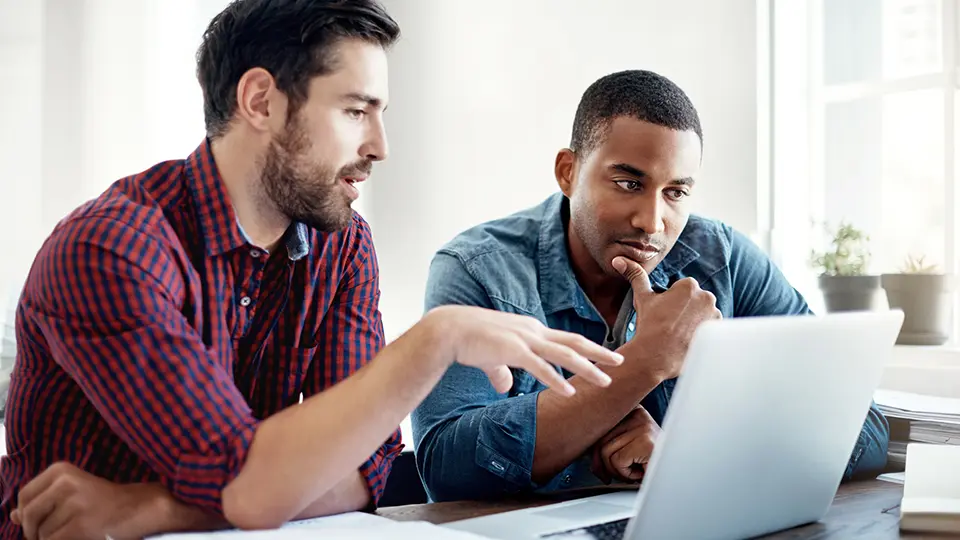 Two designers discussing something on a laptop