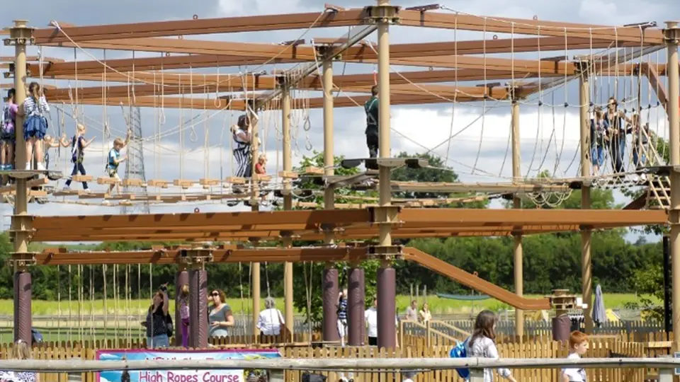 Visitors crossing suspended obstacles on a high ropes course.