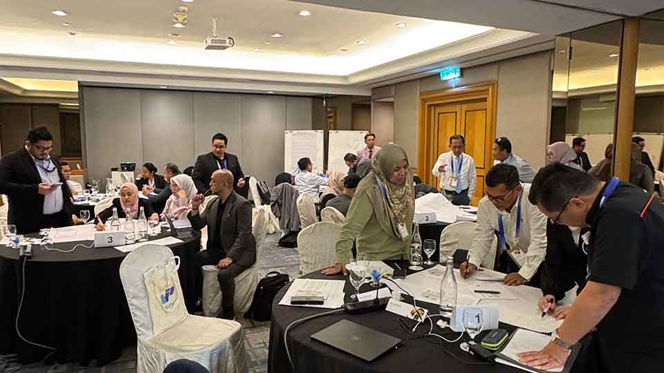 Participants discussing and taking notes during a group work session at round tables.