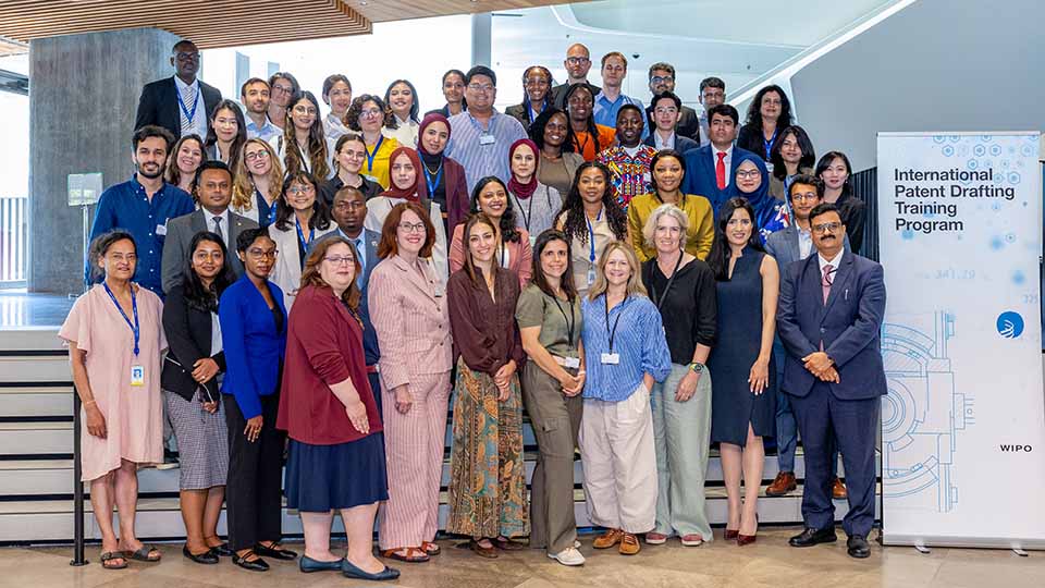 Group photo of approximately 50 international participants and WIPO facilitators of the International Patent Drafting Training Program, posed on a staircase beside an official program banner displaying the WIPO logo.