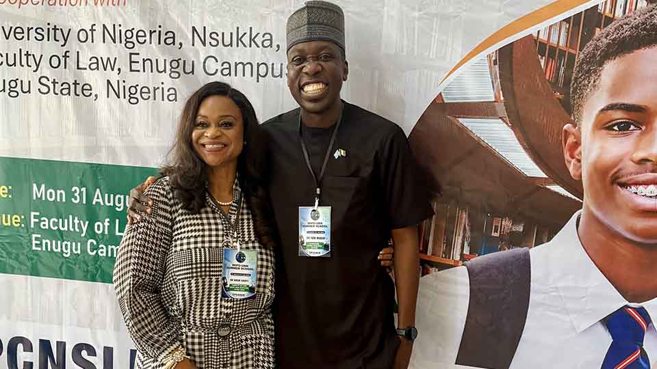 Two smiling speakers wearing event lanyards posing together in front of the WIPO-Nigeria Summer School 2026 banner
