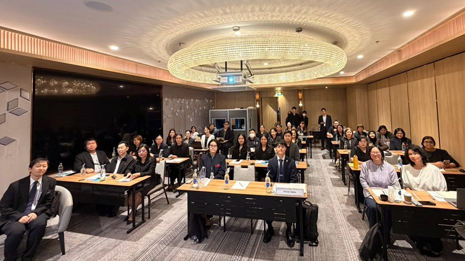 Group photo of approximately 30 seated participants and organizers in a conference room.