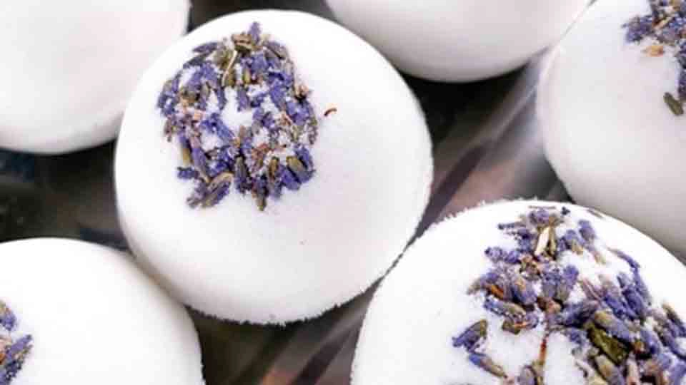Close-up of round white bath bombs topped with dried purple lavender buds, arranged closely together