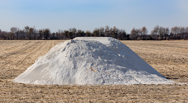 Pile of pulverized agricultural lime, limestone, fertilizer in soybean field stubble waiting fall application - stock photo