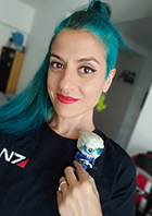 Micaela Mantegna posing with a figurine of Garrus Vakarian, a character from Mass Effect