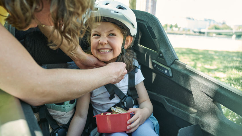 A mother straps her young daughter safely into a safety seat in Ca Go’s cargo box