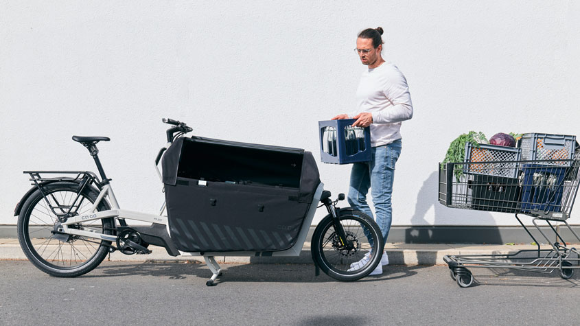 Un hombre transporta comestibles pesados en la carrocería de carga de una bicicleta modelo FS200 Vario de Ca Go
