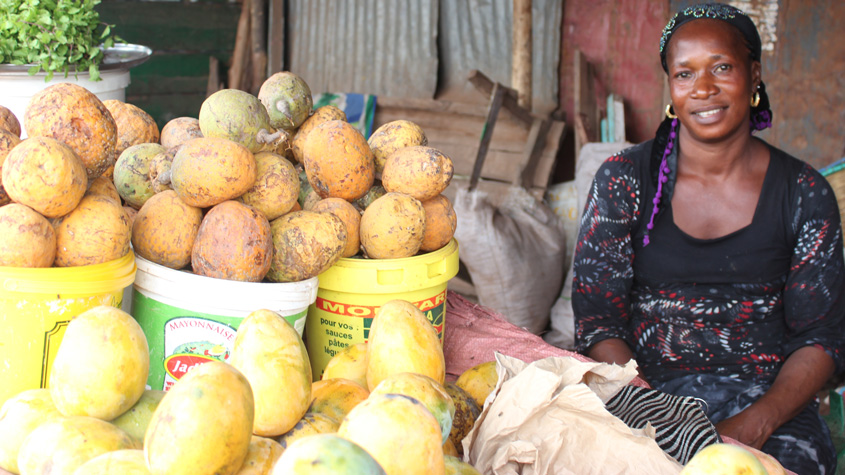 Woman sitting beside buckets full of Madd de Casamance fruits